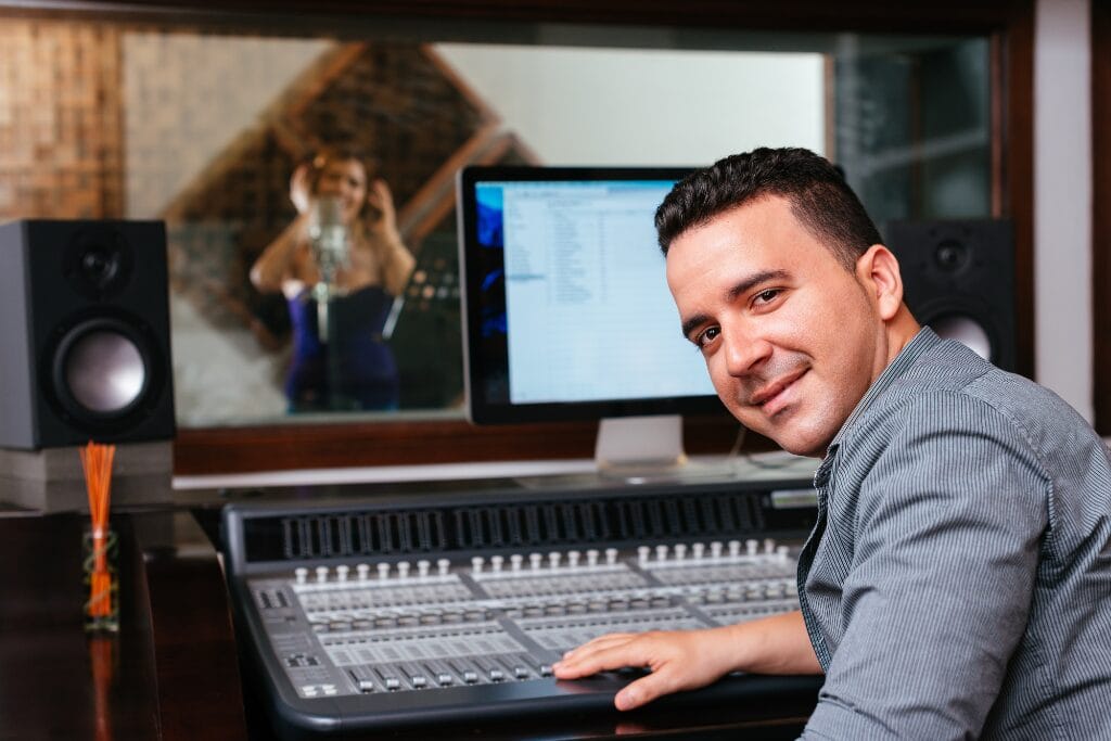 Ingénieur du son souriant devant une console de mixage dans un studio professionnel.