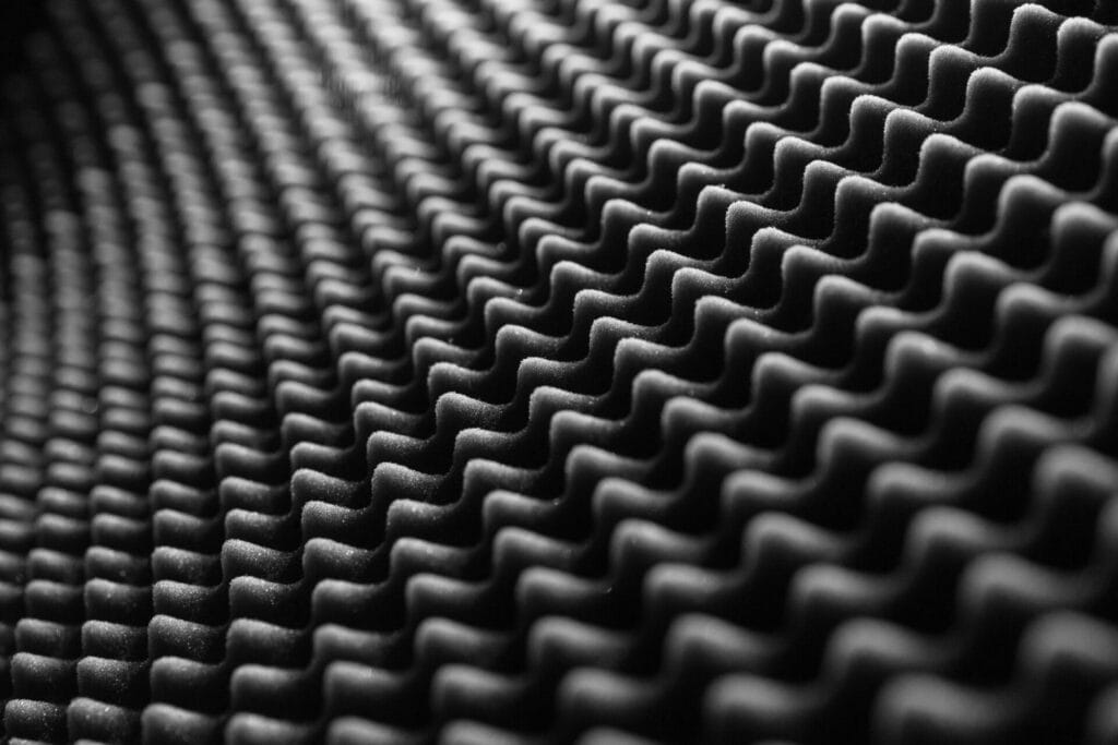 Surface texturée noire, souvent associée aux équipements ou panneaux acoustiques.